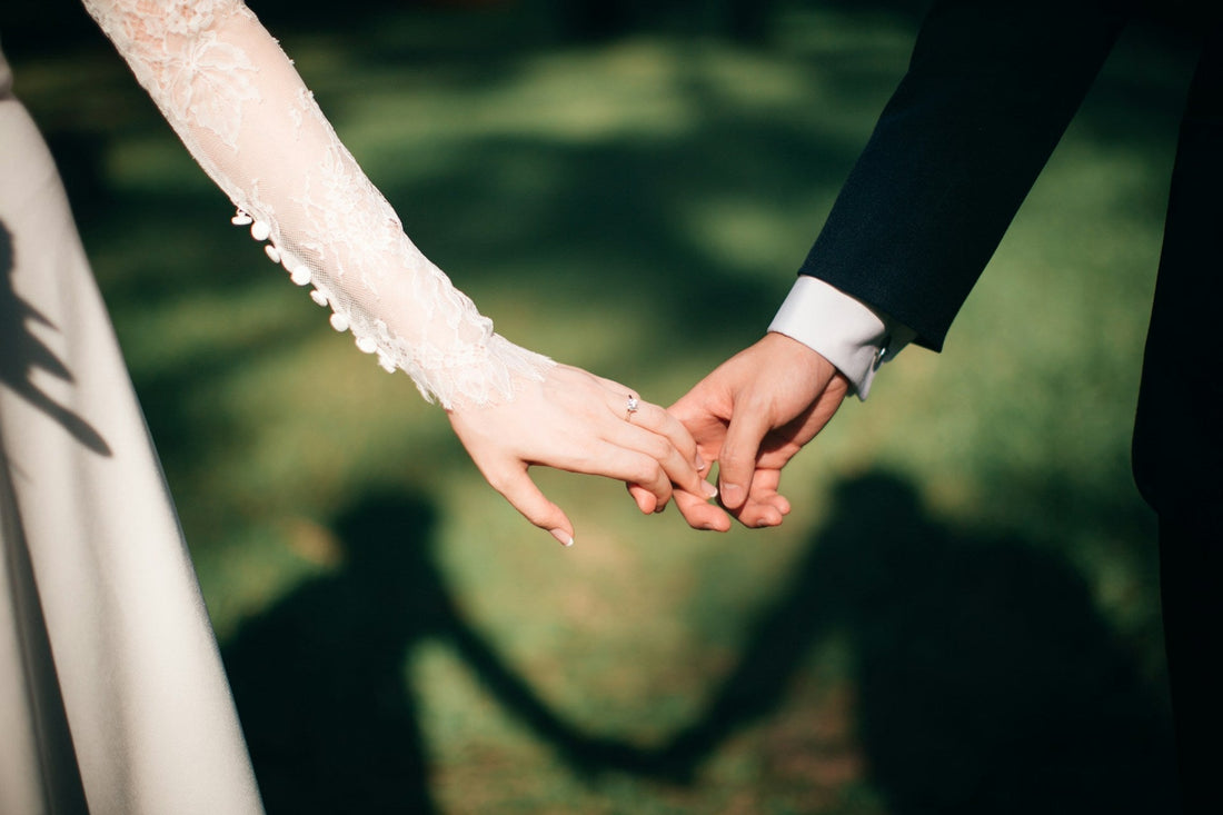 A bride and groom holding hands in a field of grass